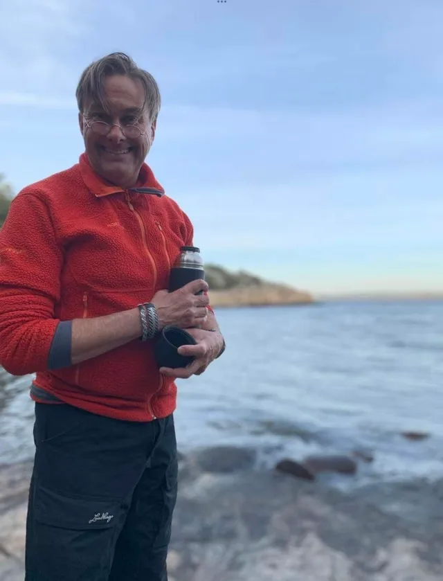 Torbjörn Källström i röd tröja med termos och kåsa vid havet