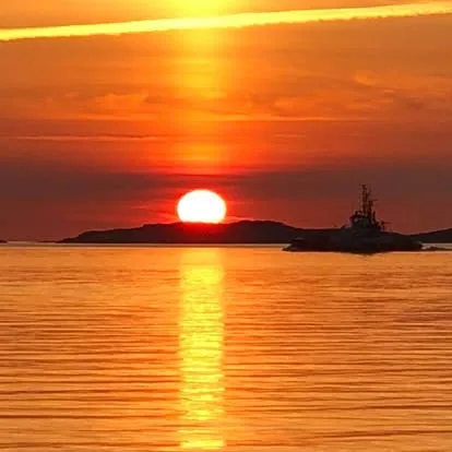 Orange solnedgång över havet med fartyg i siluett