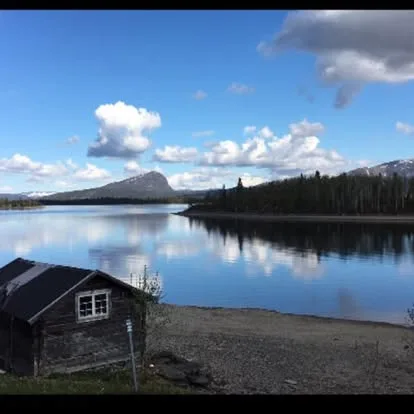 Fjällsjö med trästuga, skog och fjäll