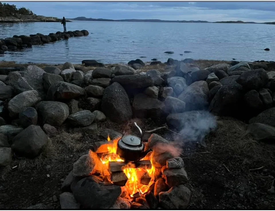 Eld med kaffepanna vid havet.